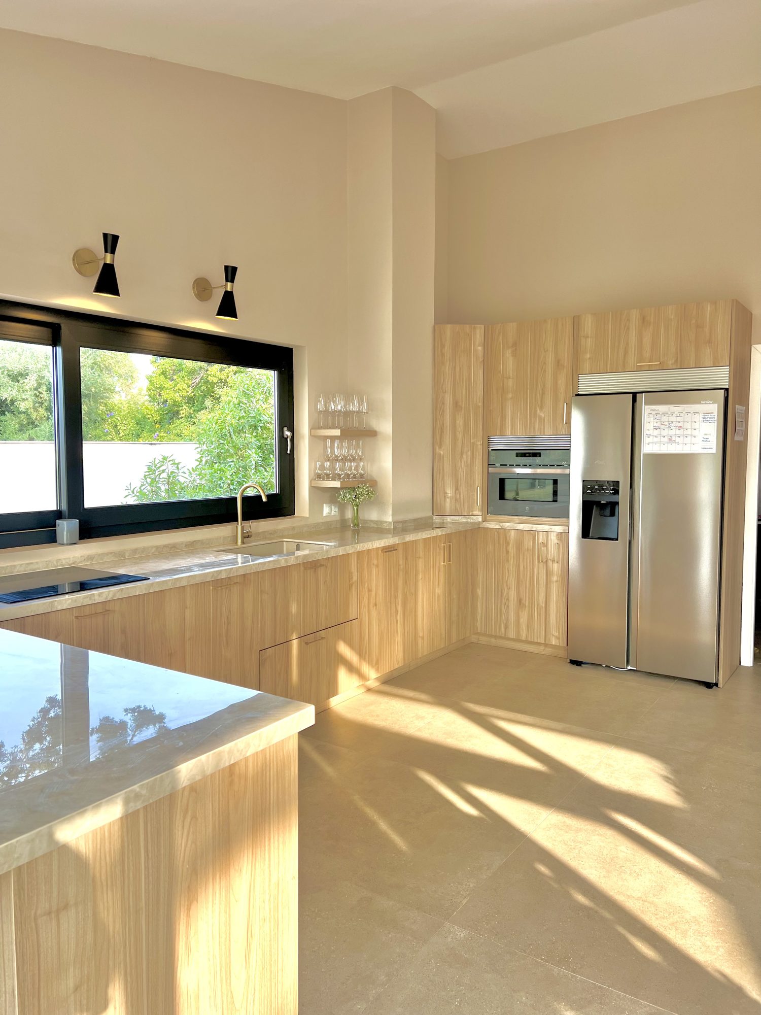 Ricmar — Main kitchen — handleless fronts, stone worktops, everything put away.
