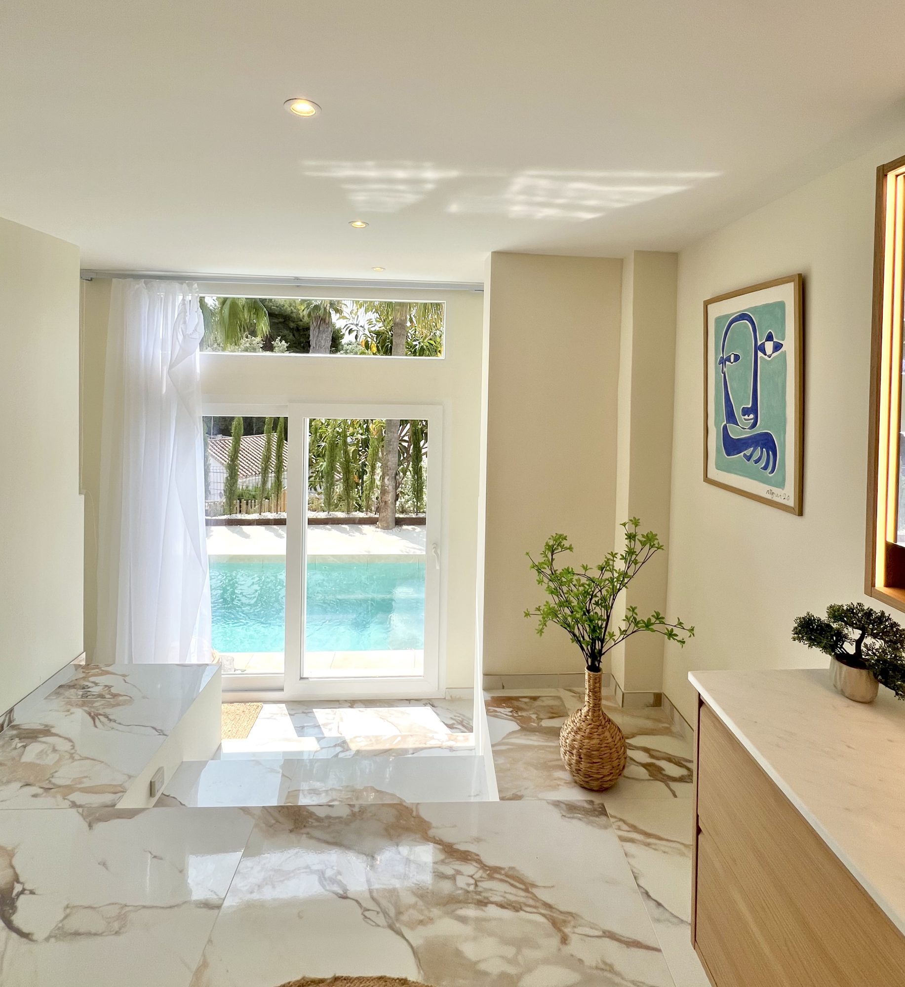 Ricmar — Pool house bathroom — book-matched marble opening straight onto the water.